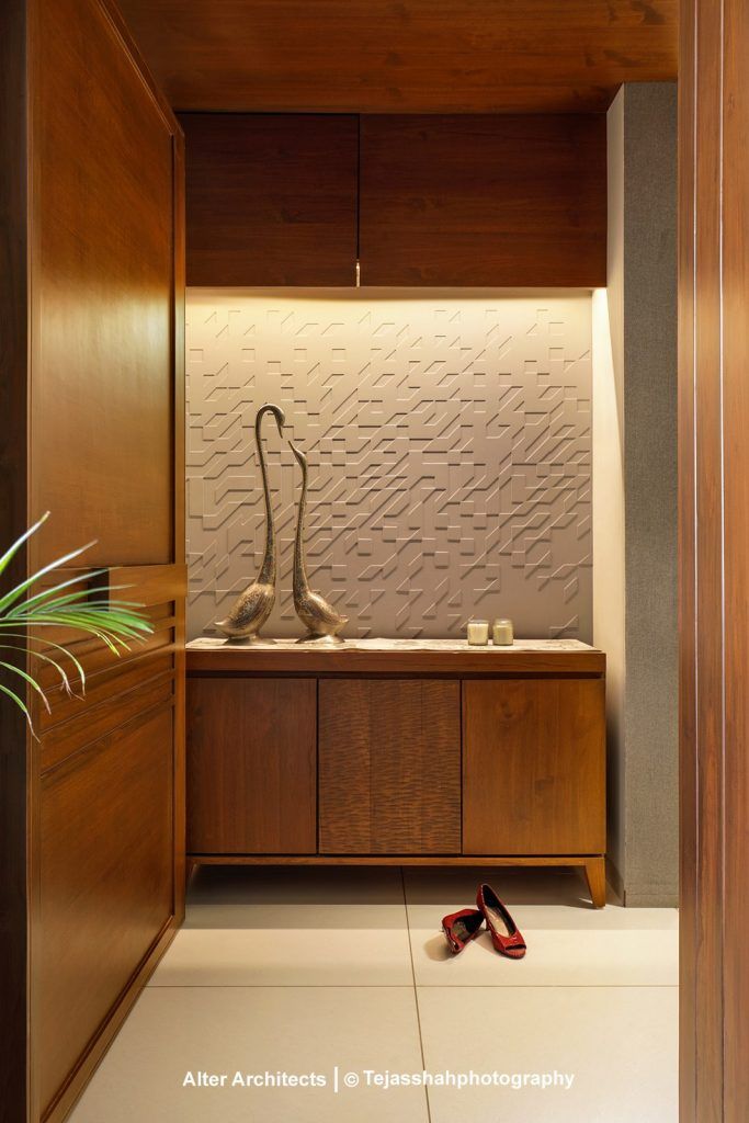 A bathroom with a wooden chair and radiator on the wall next to it in front of a wooden shelf filled with a wooden cabinet and white counter top of a vase filled with plants on the wall next